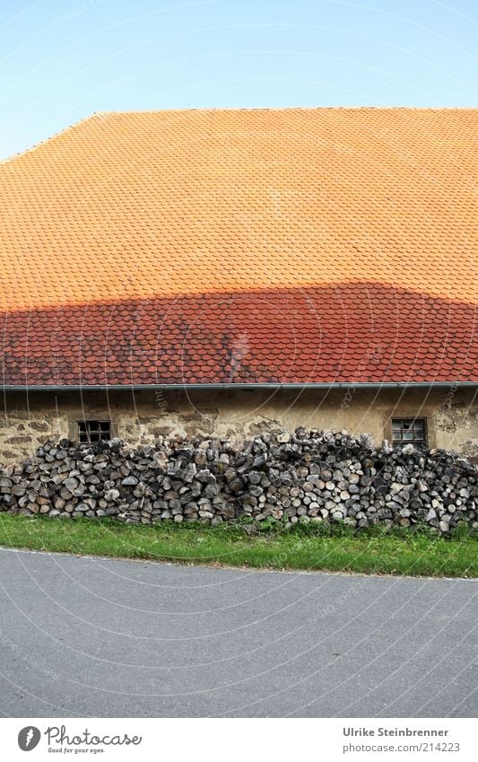Den Winter im Blick Holz Brennholz Vorrat Haus Scheune Dach Dachziegel Scheite Holzstapel Fenster Mauer grün grünstreifen orange Vorratshaltung vorausblicken
