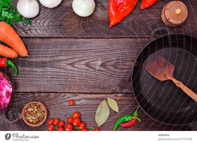 Schwarze Bratpfanne und frisches Gemüse Lebensmittel Kräuter & Gewürze Pfanne Tisch Küche Holz Metall alt rot schwarz Zwiebel Speise Mahlzeit reif Paprika Top