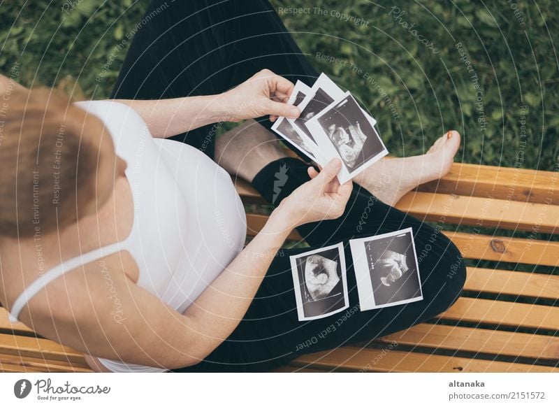 schwangere Frau sitzt auf der Bank und loocking Ultraschall-Scan am Tag Zeit. Konzept der glücklichen Erwartung. Lifestyle Glück schön Körper Leben Kind Mensch