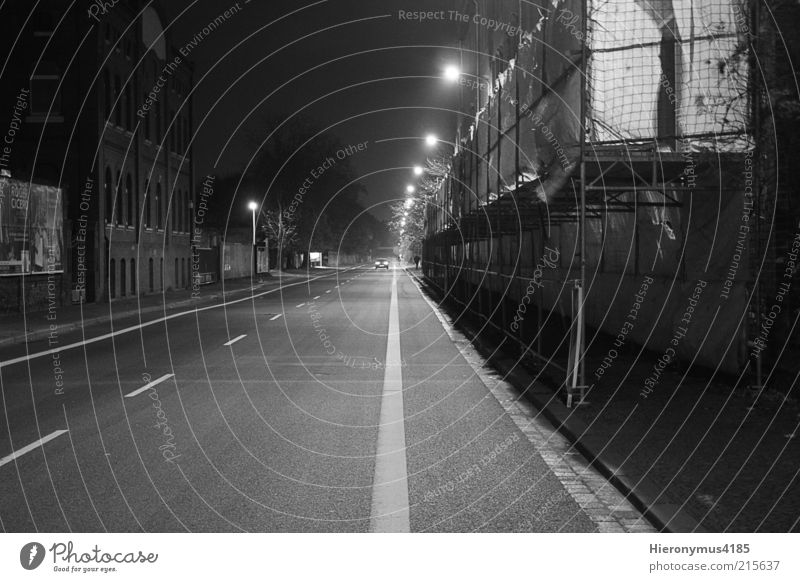 lonely road Stadtrand Menschenleer Haus Mauer Wand dunkel schwarz weiß Schwarzweißfoto Außenaufnahme Nacht Schatten Bewegungsunschärfe Totale Straßenbeleuchtung
