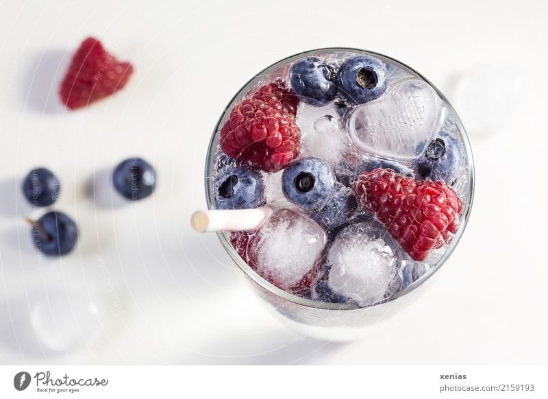Beerig fruchtiges Wasser, eisgekühlt mit Himbeeren, Heidelbeeren, Eiswürfel und Trinkhalm auf weißem Grund Getränk Erfrischungsgetränk Frucht heidelbeeren