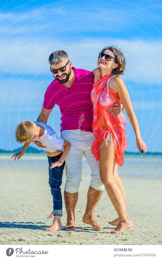 Glückliche dreiköpfige Familie am tropischen Strand, lacht und genießt die gemeinsame Zeit. Lifestyle Freude Spielen Sommer Meer Insel Kindheit Landschaft