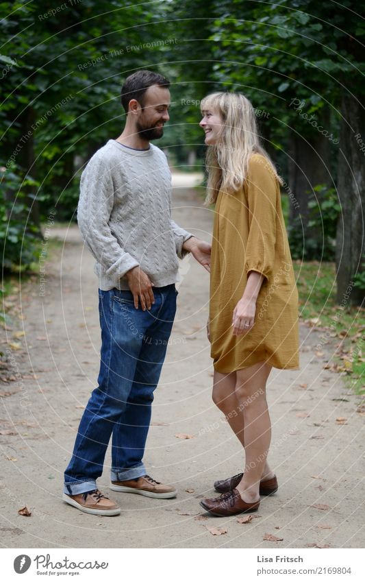 Junges lächelndes Paar auf einem Weg im Park. Partner Leben 2 Mensch 18-30 Jahre Jugendliche Erwachsene Umwelt Sommer Jeanshose Kleid langhaarig Bart berühren