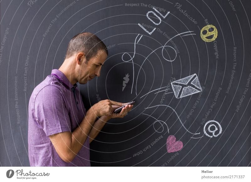 Mann mit Mobiltelefon vor mit Kreide gezeichneten Social Media Symbolen an einer Wandtafel (Thema: Social Media Overload) Lifestyle Freude Handy PDA Internet