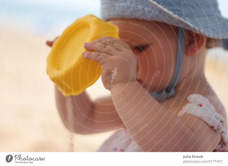 Der Sand läuft Baby Kleinkind Kindheit 1 Mensch 1-3 Jahre Sommer Schönes Wetter Wärme Strand Hut festhalten Blick Neugier niedlich blau gelb Gelassenheit