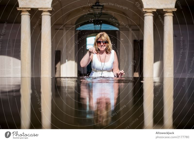 Frau mit Sonnenbrille spielt mit Wasser Tag 1 Mensch feminin Junge Frau blond langhaarig Kleid Brunnen Becken Erfrischung Sommer Säule Reflexion & Spiegelung