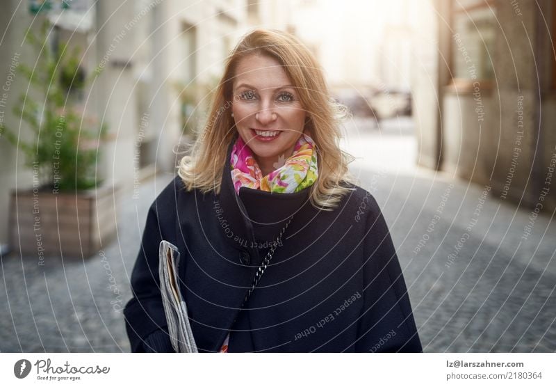 Blonde reife lächelnde Frau auf Straße elegant Glück Gesicht Business Erwachsene 1 Mensch 30-45 Jahre Zeitung Zeitschrift Fußgänger Mantel blond Lächeln