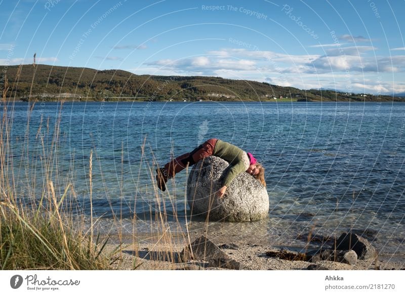 Junge Frau liegt lustig auf einem Stein im Meer, Fjord Erholung Jugendliche Natur Schönes Wetter Gras Felsen Küste Lofoten liegen schlafen träumen Umarmen