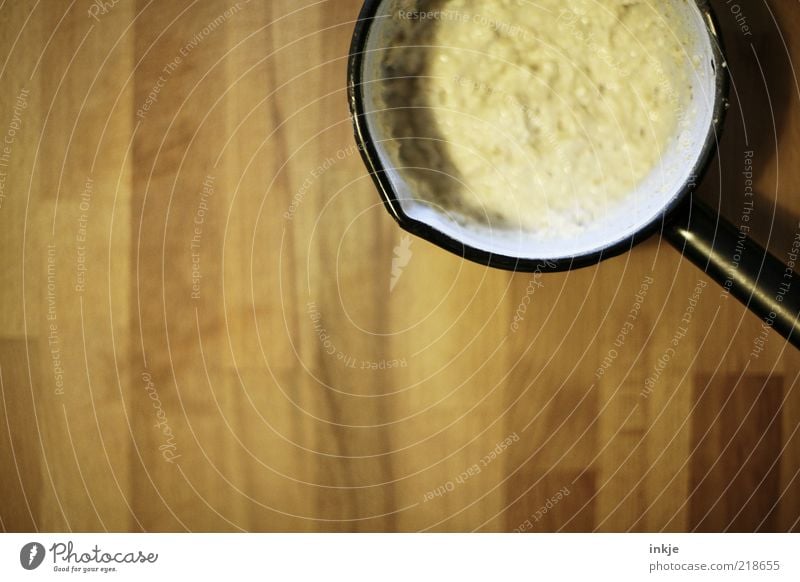 Omas Breitopf Porridge Ernährung Vegetarische Ernährung Topf Tisch Emaille Holz schleimig braun gelb schwarz Holztisch Haferbrei Bildausschnitt Anschnitt