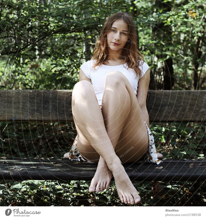 Junge, sehr athletische Frau in Rock und T-Shirt sitzt im Wald auf einer Holzbank barfuß mit den Beinen gekreuzt Freude schön Leben Wohlgefühl Ausflug Abenteuer