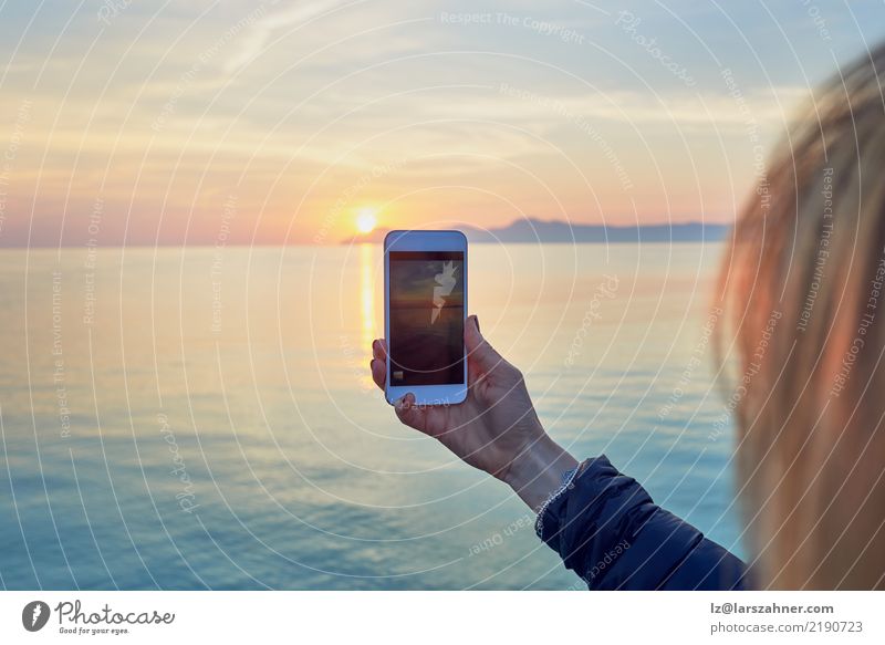 Junge Frau, die ein Foto eines bunten Ozeansonnenuntergangs macht Ferien & Urlaub & Reisen Sightseeing Sommer Sonne Meer Handy PDA Fotokamera