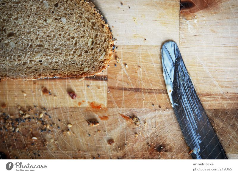 Moin - Frühstück! Lebensmittel Brot Krümel Brotkrümel Ernährung Abendessen Bioprodukte Vegetarische Ernährung Messer Schneidebrett Tisch braun Körnerbrot