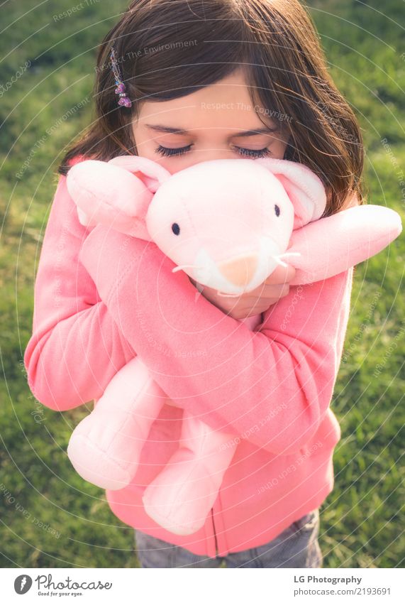 Junges Mädchen kuschelt stuffy Glück Spielen Sonne Ostern Mensch Frau Erwachsene Hand Gras Spielzeug Puppe Teddybär Umarmen niedlich Sauberkeit grün rosa