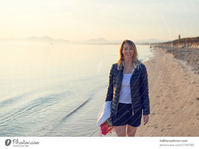 Blonde lächelnde Frau, die entlang Strand geht Glück Ferien & Urlaub & Reisen Tourismus Meer Erwachsene Sand blond heiter laufen sonnig Sonnenuntergang Tourist