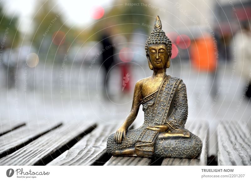 Kleine Buddha Figur sitzt in Meditationshaltung auf einer Bank mitten in der Großstadt harmonisch Erholung ruhig Kunst Kunstwerk Skulptur Stadtzentrum