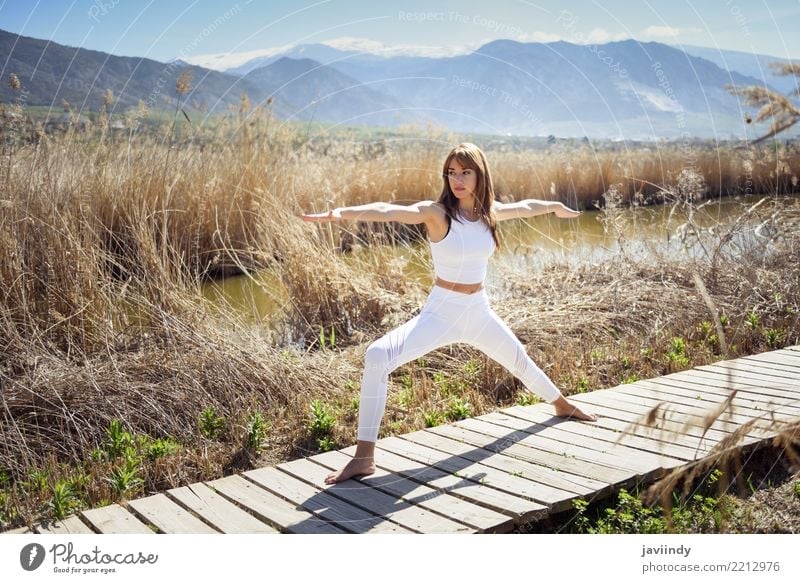 Junge Frau, die Yoga in der Natur tut. Lifestyle schön Wellness Erholung Meditation Sommer Sport Mensch Erwachsene Fitness dünn weiß Krieger Pose 2 Hintergrund