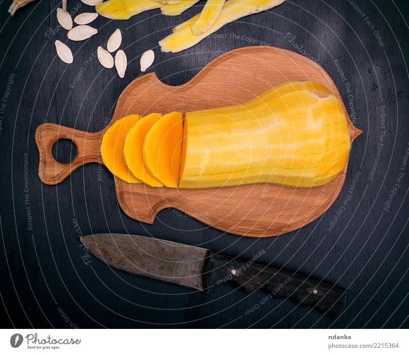 geschnittener frischer geschälter Kürbis Gemüse Essen Abendessen Vegetarische Ernährung Messer Tisch Halloween Natur Holz oben gelb schwarz Tradition