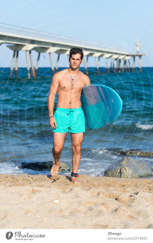 Junger attraktiver Surfer, der sein Surfbrett am Strand hält Lifestyle Freude Ferien & Urlaub & Reisen Sommer Meer Wellen Sport Mann Erwachsene Jugendliche