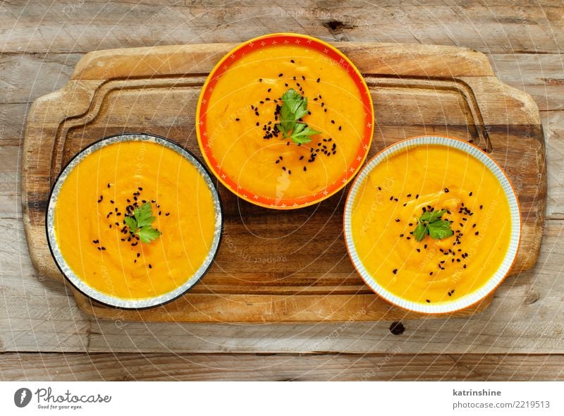 Frische Kürbissuppe in drei Schüsseln auf einem Holztisch Gemüse Suppe Eintopf Vegetarische Ernährung Schalen & Schüsseln Tisch Erntedankfest Halloween Herbst