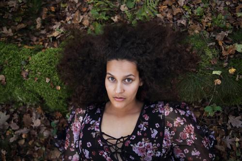 Portrait im Wald einer jungen, schönen Frau mit langen, dunklen Haaren und vielen Locken, die auf dem Waldboden liegt Glück Haare & Frisuren Gesicht Wohlgefühl