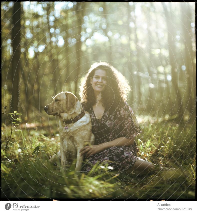 analoges Mittelformatbild eines jungen, blonden Labradors mit einer jungen, dunkelhaarigen Frau mit wilden Locken im Wald im Gegenlicht Glück schön harmonisch