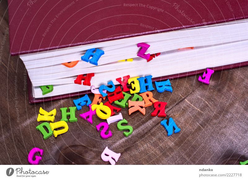 mehrfarbige Buchstaben des englischen Alphabets Tisch Holz lernen blau braun rosa rot Brief Information farbenfroh zugeklappt Deckung Wissen Farbfoto