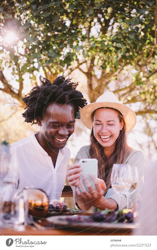 Glückliche junge erwachsene Paare, die Videos am Telefon aufpassen Lifestyle Freude Sommer Tisch Restaurant Technik & Technologie Erwachsene Afro-Look Lächeln