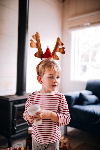 Tragendes Renohrskostüm des netten Kleinkindes am Weihnachtstag trinken Lifestyle Freude Glück Winter Haus Wohnzimmer Weihnachten & Advent Kind Wärme Lächeln