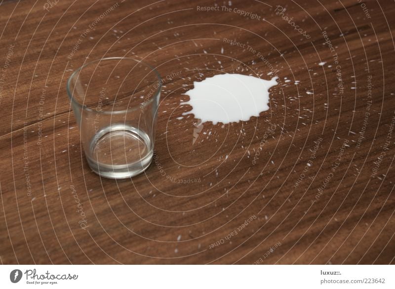 Halb voll oder halb leer? Milch klecksen Glas Tropfen verschütten tollpatschig Fehler durstig milk Fleck Getränk verlieren Hintergrund neutral Holz Seite