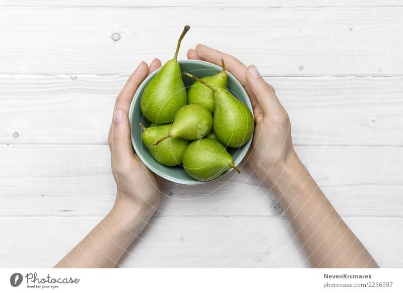 Weibliche Hände, die eine Schüssel grüne Birnen halten Lebensmittel Frucht Ernährung Essen Frühstück Mittagessen Abendessen Picknick Schalen & Schüsseln Topf