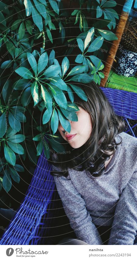 Junge Frau versteckt hinter einer Pflanze Lifestyle Stil exotisch Sinnesorgane Erholung Innenarchitektur Sofa Dachboden Mensch feminin Jugendliche 1 18-30 Jahre