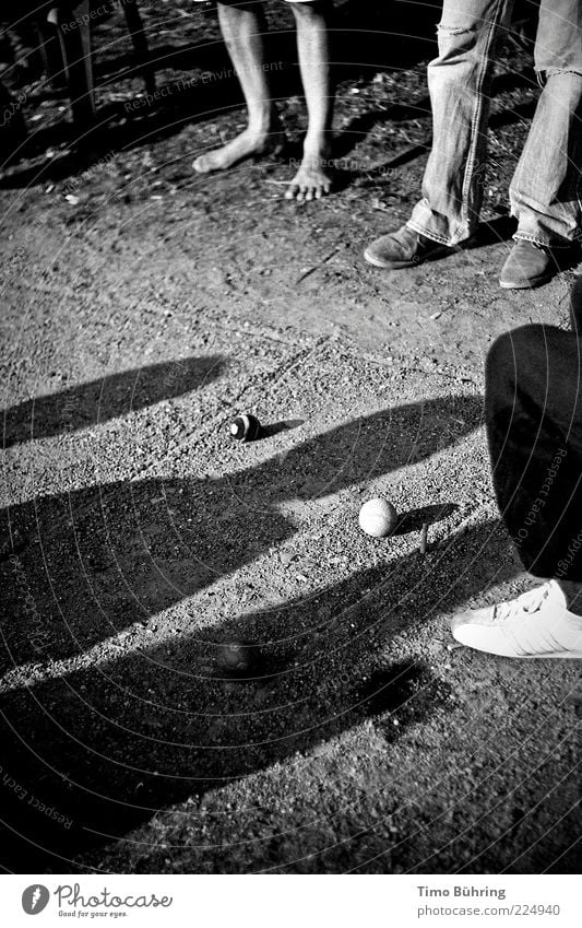 Schattenspiel Mensch Beine Fuß 3 Erde Sonnenlicht Sand Kugel Spielen stehen einfach natürlich schwarz weiß Kies Schwarzweißfoto Außenaufnahme Textfreiraum links