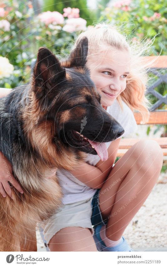 Junges lächelndes Mädchen, das im Garten hockt und ihren Hund umarmt Glück Sommer Mensch Frau Erwachsene Freundschaft 1 13-18 Jahre Jugendliche Tier Haustier