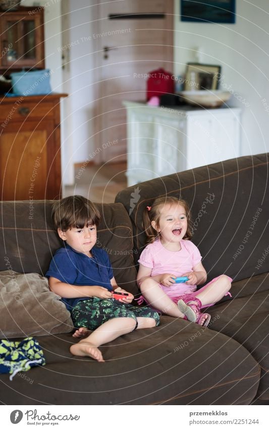 Kinder spielen ein Videospiel auf dem Sofa zu Hause Lifestyle Freude Glück Freizeit & Hobby Spielen Häusliches Leben Technik & Technologie Kleinkind Mädchen