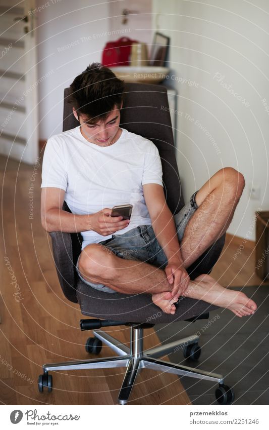 Entspannter Junge, der mit den Freunden unter Verwendung des intelligenten Telefons plaudert Lifestyle Glück Erholung Stuhl Handy PDA Technik & Technologie