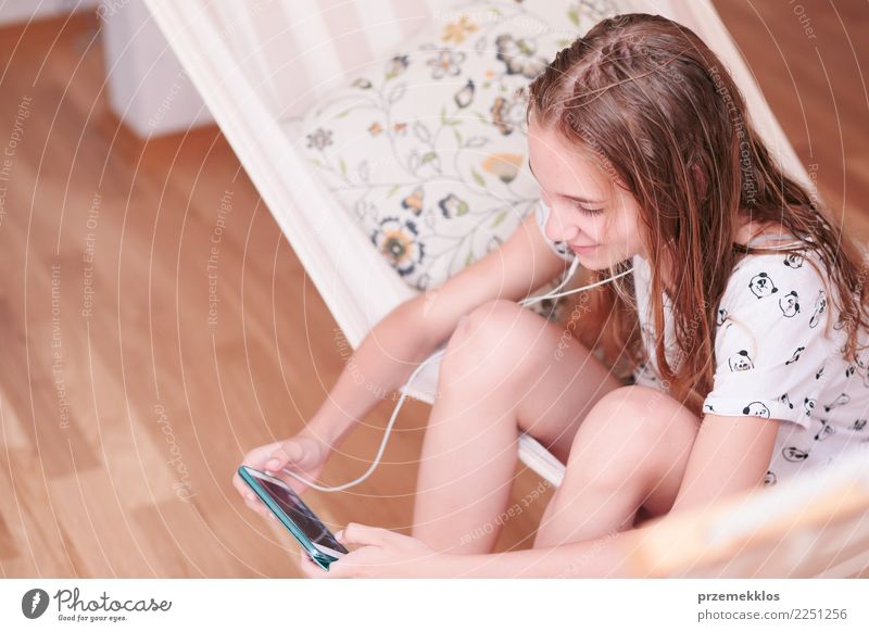 Teenager-Mädchen hört Musik und chattet mit Freunden auf dem Smartphone in der Hängematte zu Hause Lifestyle kaufen Freizeit & Hobby Kind Telefon Funktelefon