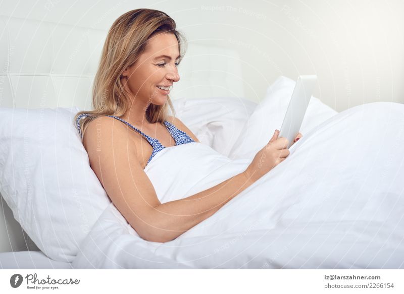 Attraktive Frau, die im Bett mit einem Tablet-Computer sich entspannt kaufen Freude Glück schön Erholung Schlafzimmer Technik & Technologie Internet Erwachsene