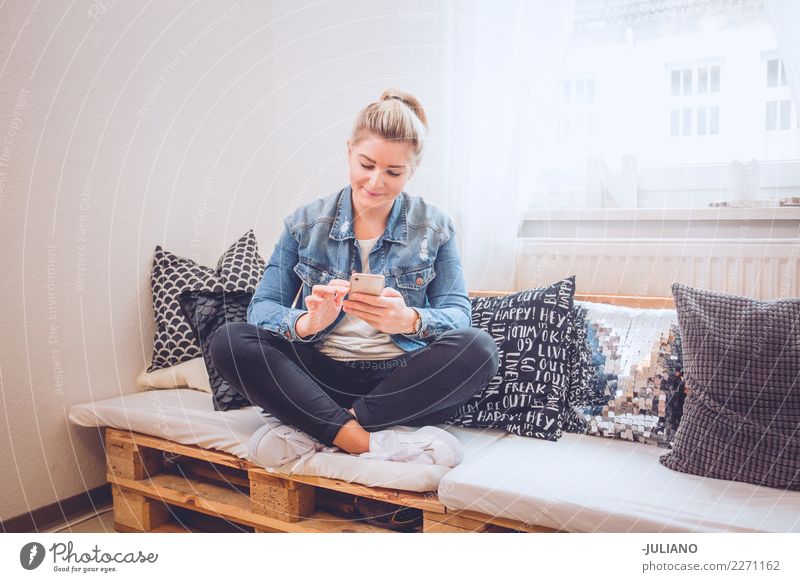 junge Frau, die auf ihrer diy Couch mit Telefon sitzt Lifestyle kaufen Ferien & Urlaub & Reisen Häusliches Leben Wohnung Innenarchitektur Raum Wohnzimmer Mensch