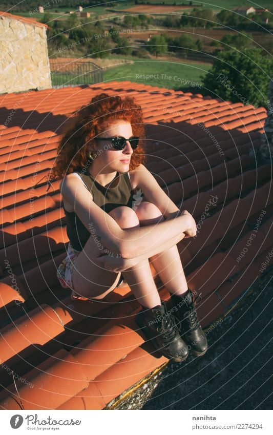 Junge rothaarige Frau, die auf einem Dach sitzt. Lifestyle Stil Haare & Frisuren Wellness Wohlgefühl Sinnesorgane Erholung Ferien & Urlaub & Reisen Tourismus