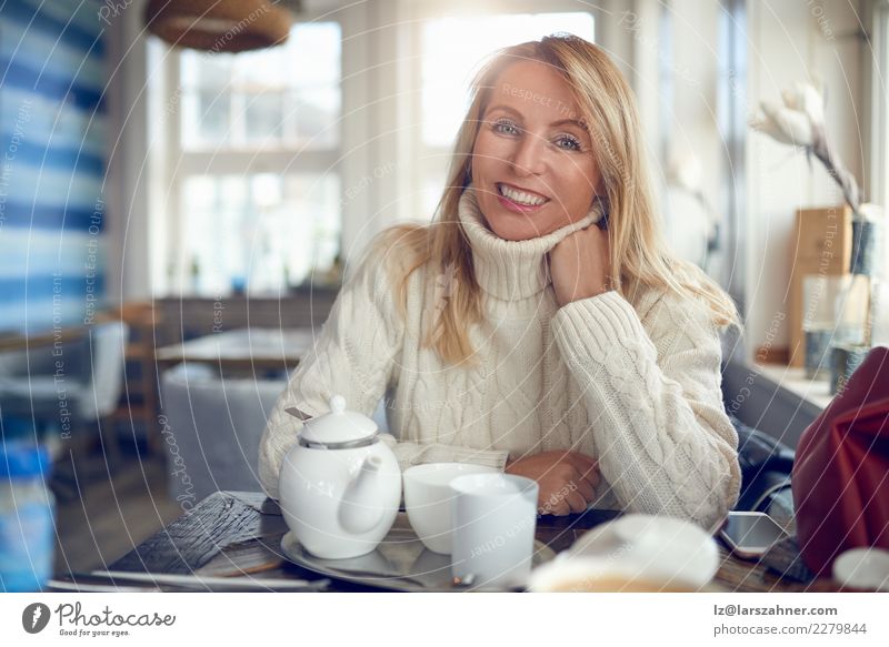 Portrait einer schönen Frau, die Kamera betrachtet trinken Kaffee Tee Topf Glück Gesicht ruhig Freizeit & Hobby Winter Tisch Erwachsene 1 Mensch 45-60 Jahre