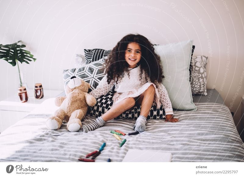 Kleines afrikanisches Mädchen sitzt auf dem Bett, mit Teddybär lächelnd. Freude Glück schön Spielen Kind Mensch Kindheit lachen sitzen springen Fröhlichkeit