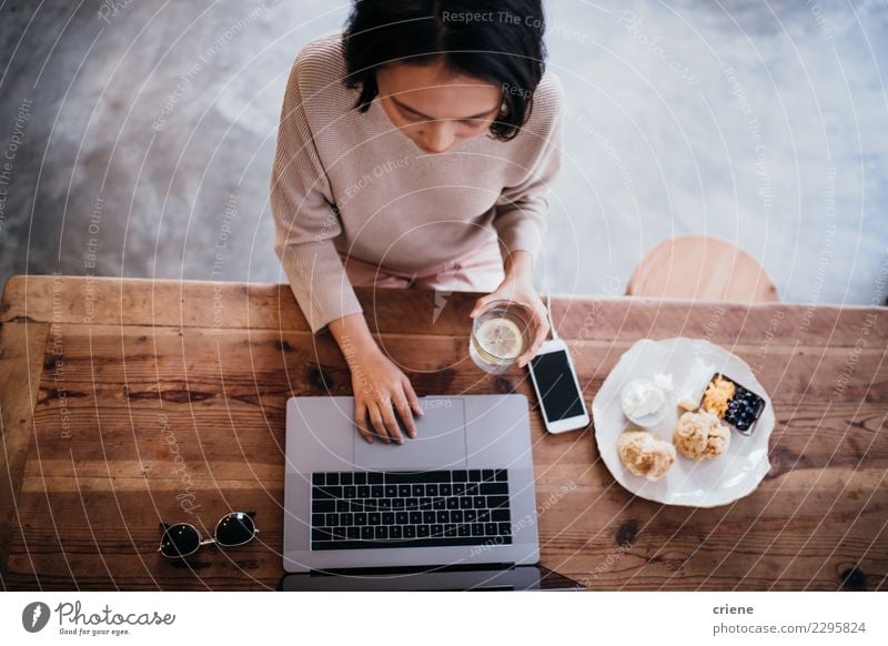 Junge erwachsene Frau, die an Laptop im Café arbeitet Essen Frühstück Kaffee Teller Lifestyle Tisch Arbeit & Erwerbstätigkeit Büro Business PDA Computer