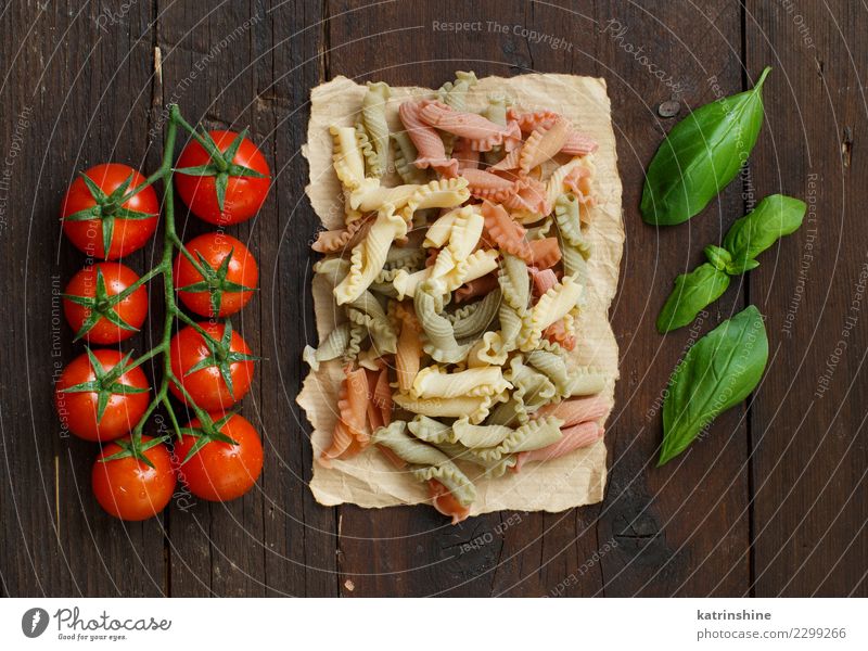 Dreifarbige Nudeln, Tomaten und Basilikum auf Holzuntergrund Vegetarische Ernährung Diät Tisch dunkel frisch braun rot Tradition Essen zubereiten Lebensmittel