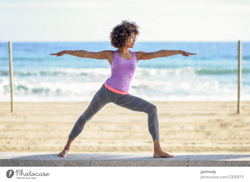 Schwarze Frau beim Yoga in Kriegerpose am Strand. Lifestyle schön Körper Haare & Frisuren Wellness Erholung Meditation Freizeit & Hobby Meer Sport Mensch