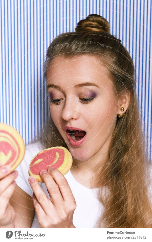 Young woman eating 2 cookies. feminin Junge Frau Jugendliche Erwachsene 1 Mensch 18-30 Jahre genießen Ernährung Mürbeplätzchen Keks Cookies Vorfreude Süßwaren