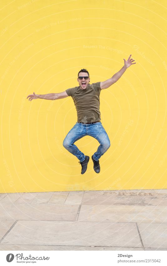 Junger Mann mit springender Sonnenbrille Lifestyle Freude Freiheit Mensch Jugendliche Erwachsene T-Shirt Jeanshose Bewegung authentisch einzigartig gelb