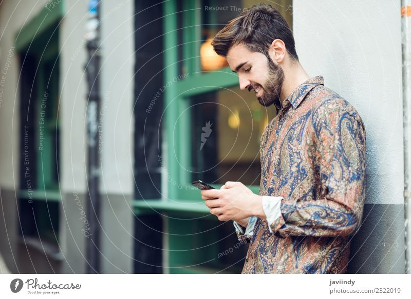 Junger lächelnder Mann schaut auf sein Smartphone auf der Straße. Lifestyle Stil schön Haare & Frisuren Telefon PDA Mensch maskulin Junger Mann Jugendliche