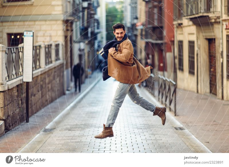 Junger Mann hüpfend in Winterkleidung auf der Straße Lifestyle elegant Stil Freude Glück Mensch Erwachsene Herbst Mode Bekleidung Jeanshose Mantel Schal
