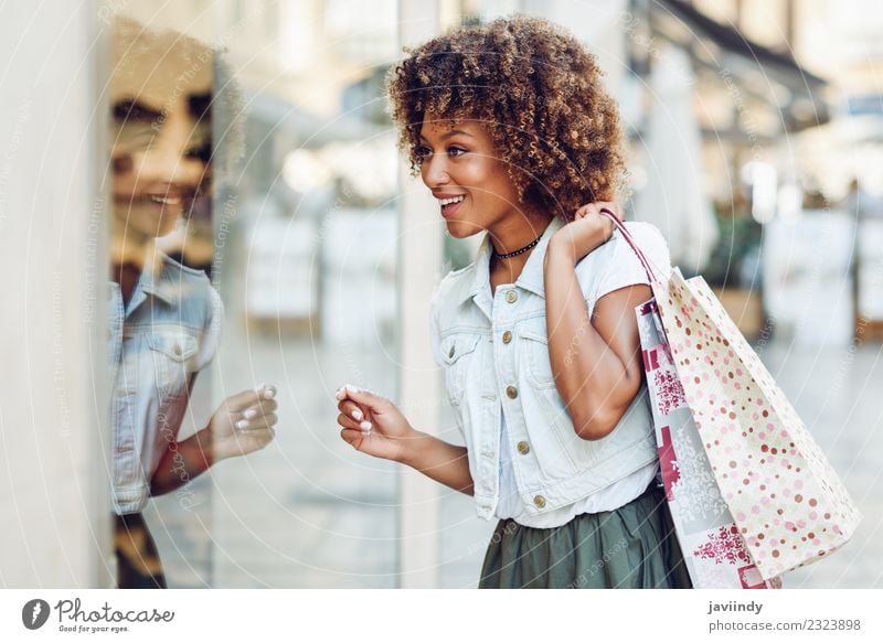 Junge schwarze Frau vor einem Schaufenster in einer Einkaufsstraße Lifestyle kaufen Stil Haare & Frisuren Mensch feminin Junge Frau Jugendliche Erwachsene 1