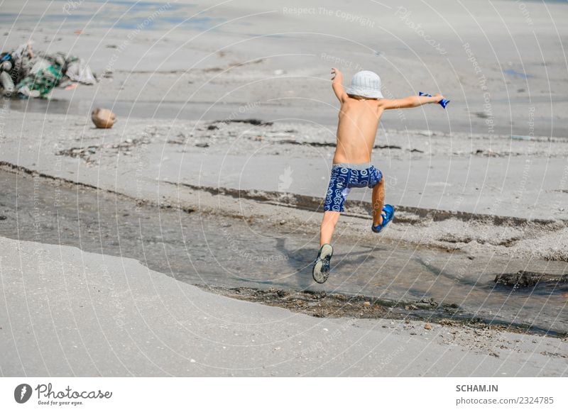 Siebenjähriger Junge, der über den kleinen Fluss springt. Lifestyle Freude Spielen Sommer Meer Insel Mensch Kind Kindheit 1 3-8 Jahre Landschaft Hut Lächeln